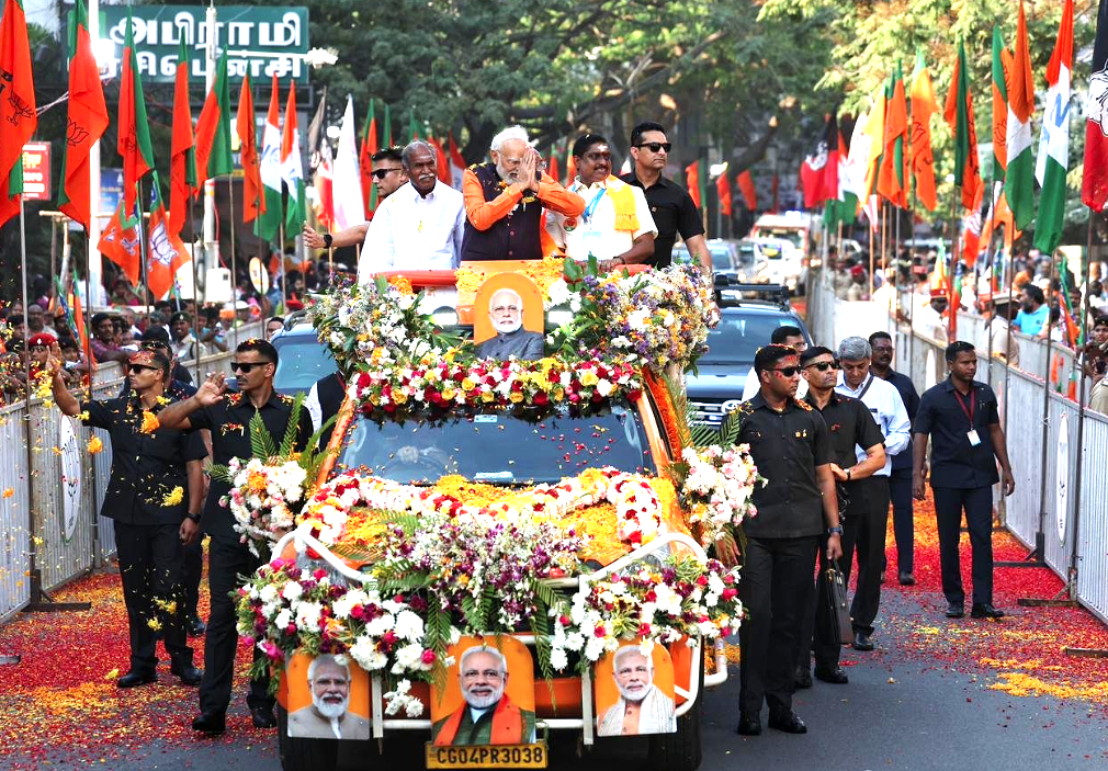 Prime Minister Narendra Modi waves to supporters during a roadshow in Puducherry ahead of the 2026 assembly elections, joined by Chief Minister N. Rangaswamy and party leaders.