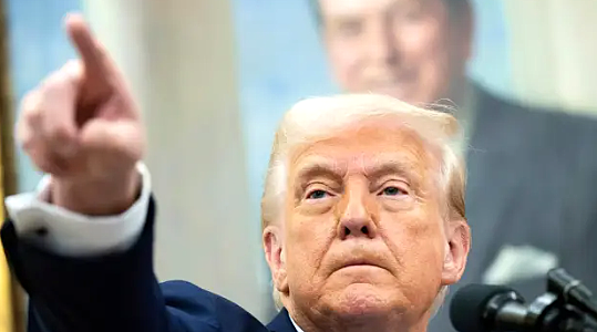Donald Trump speaking at a political event with overlay text referencing “storm coming” post and rising US-Iran tensions.